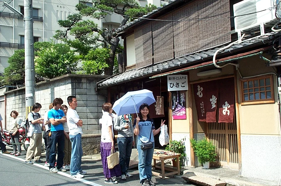 午餐店外排隊時，太太撐傘對鏡頭比 YA