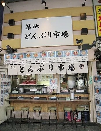 築地どんぶり市場店面,櫃檯上方掛著菜單照片與招牌。