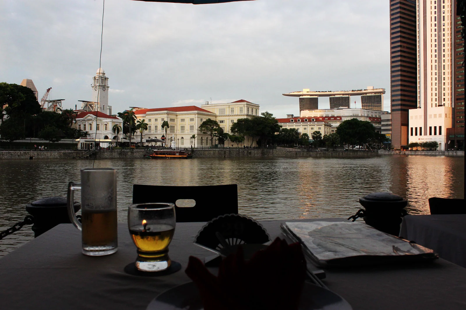 新加坡河畔餐桌上的 Tiger Beer,對岸建築在背景中。
