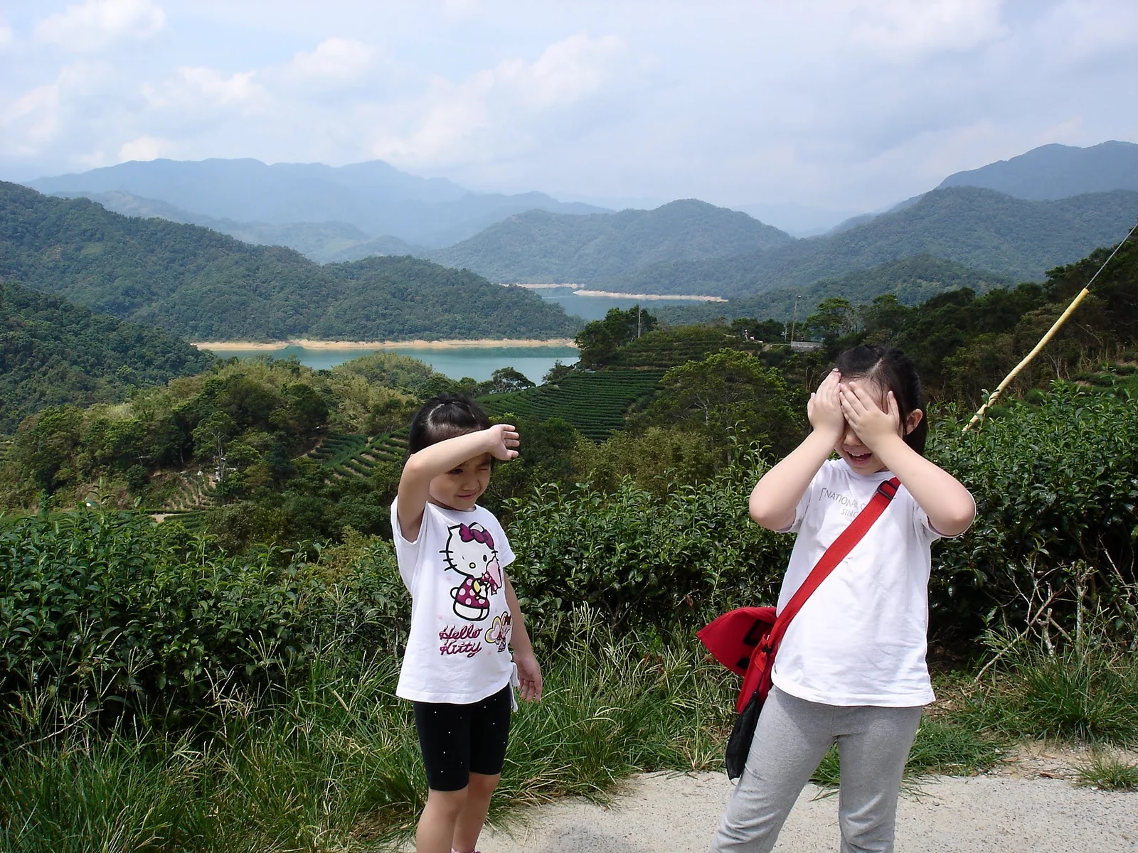 兩個孩子在石碇山景前迎著陽光合照